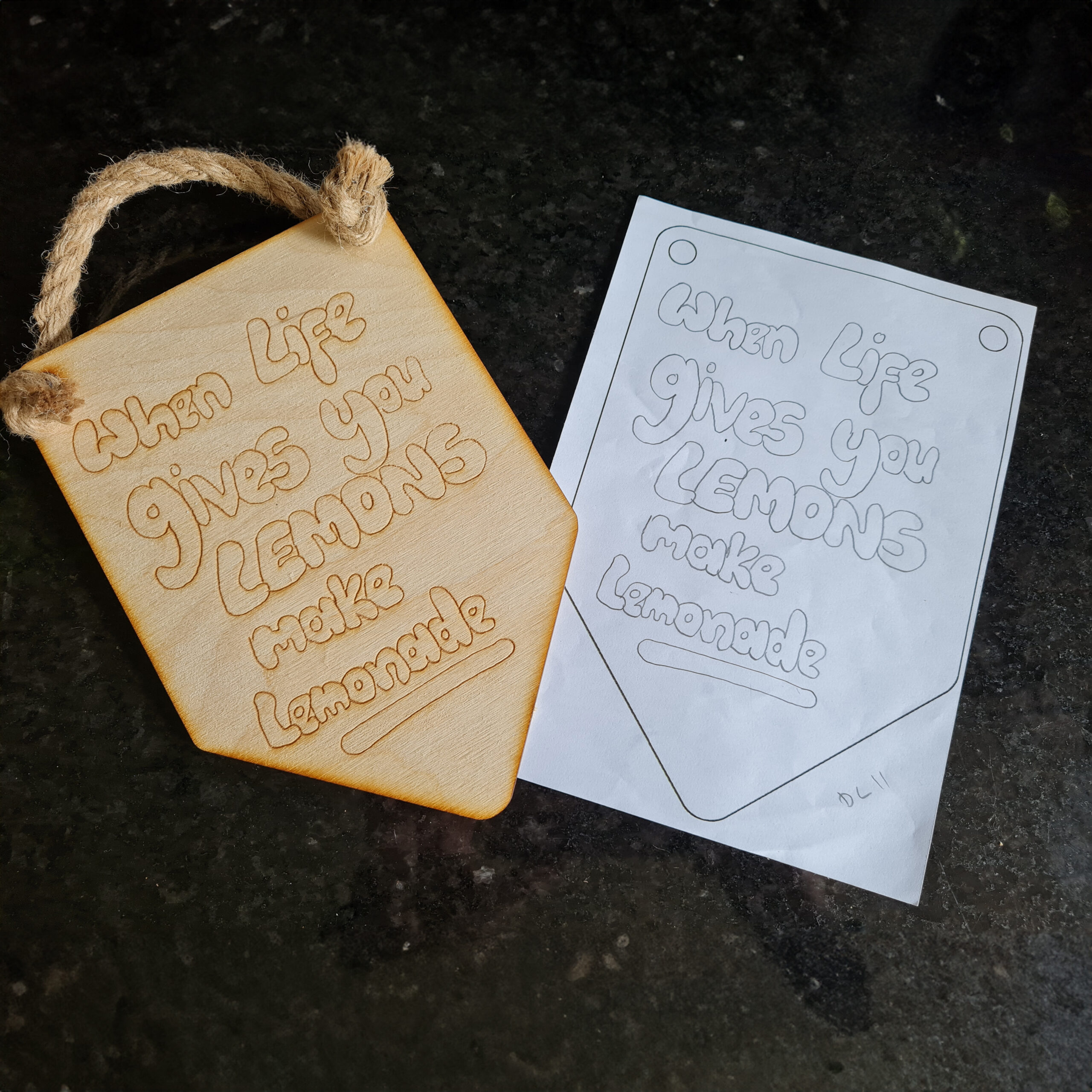 Paper drawing with personalised artwork drawn onto it and wooden sign with the personalised artwork laser engraved onto it.
