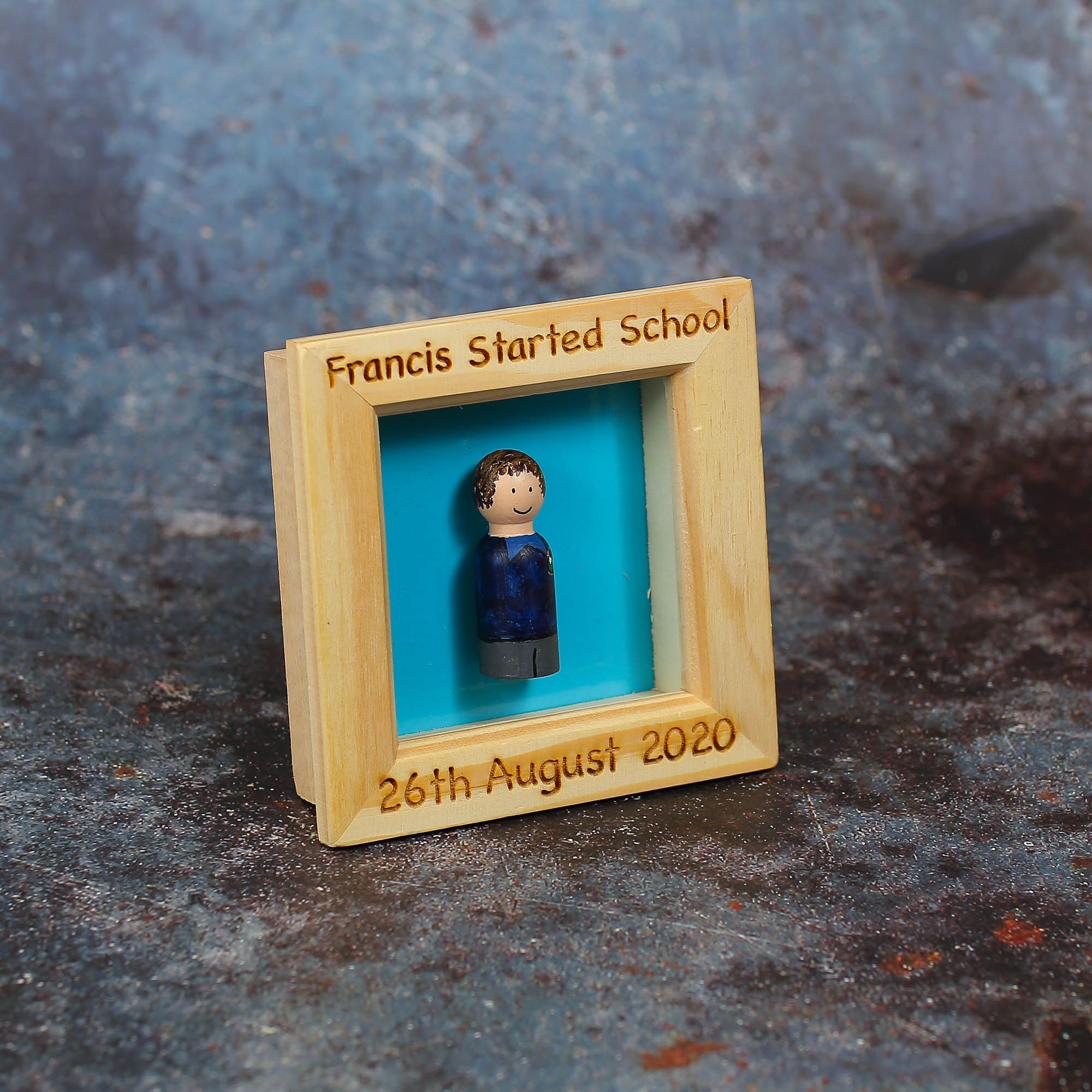 Frame with painted peg doll in the centre with the name of the child starting school and the date they started.