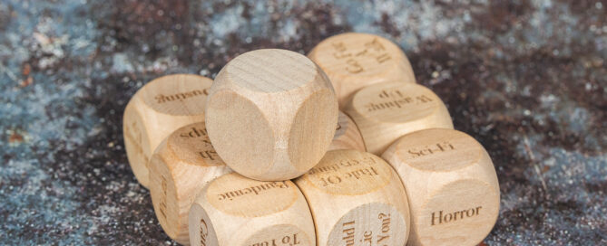 Several laser engraved dice with things such as Horror, sci-fi, Would I lie to you engraved on them.