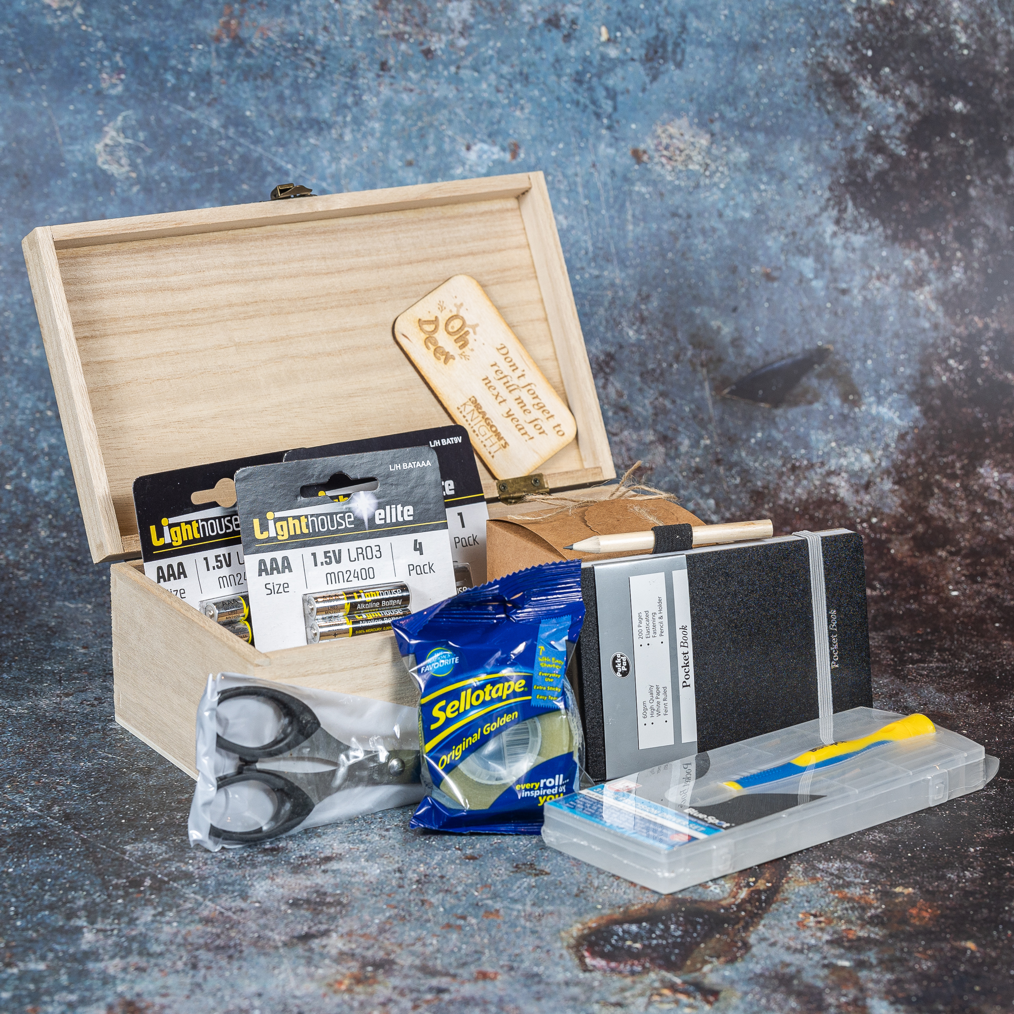Box filled with various items including sellotape, batteries and scissors.