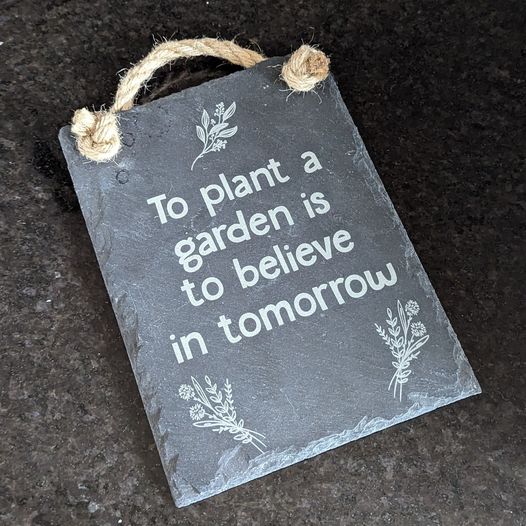 Slate sign laser engraved with To plant a garden is to believe in tomorrow and some floral imagery.