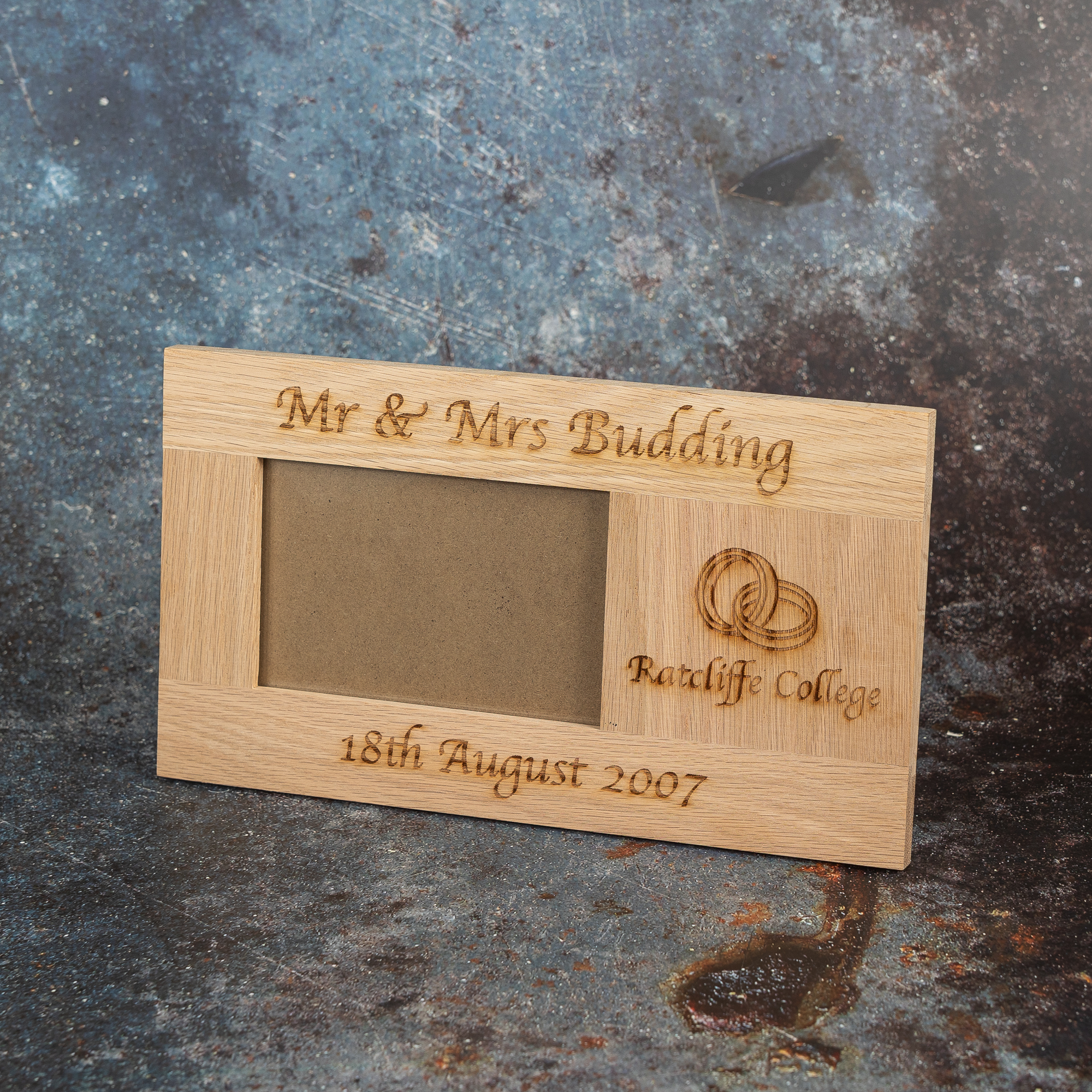 Personalised wooden frame with couples name and wedding date details. There is also imagery of a pair of entwined wedding rings and the wedding venue details.