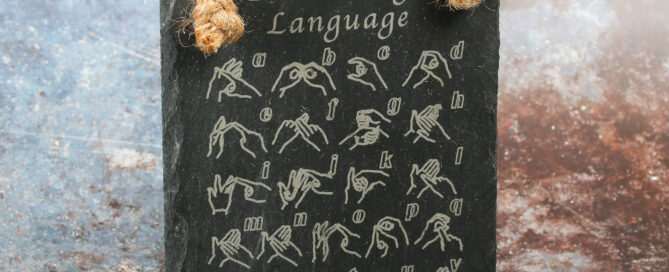 Slate sign engraved with the British Sign Language fingerspelling alphabet and jute hanging rope.