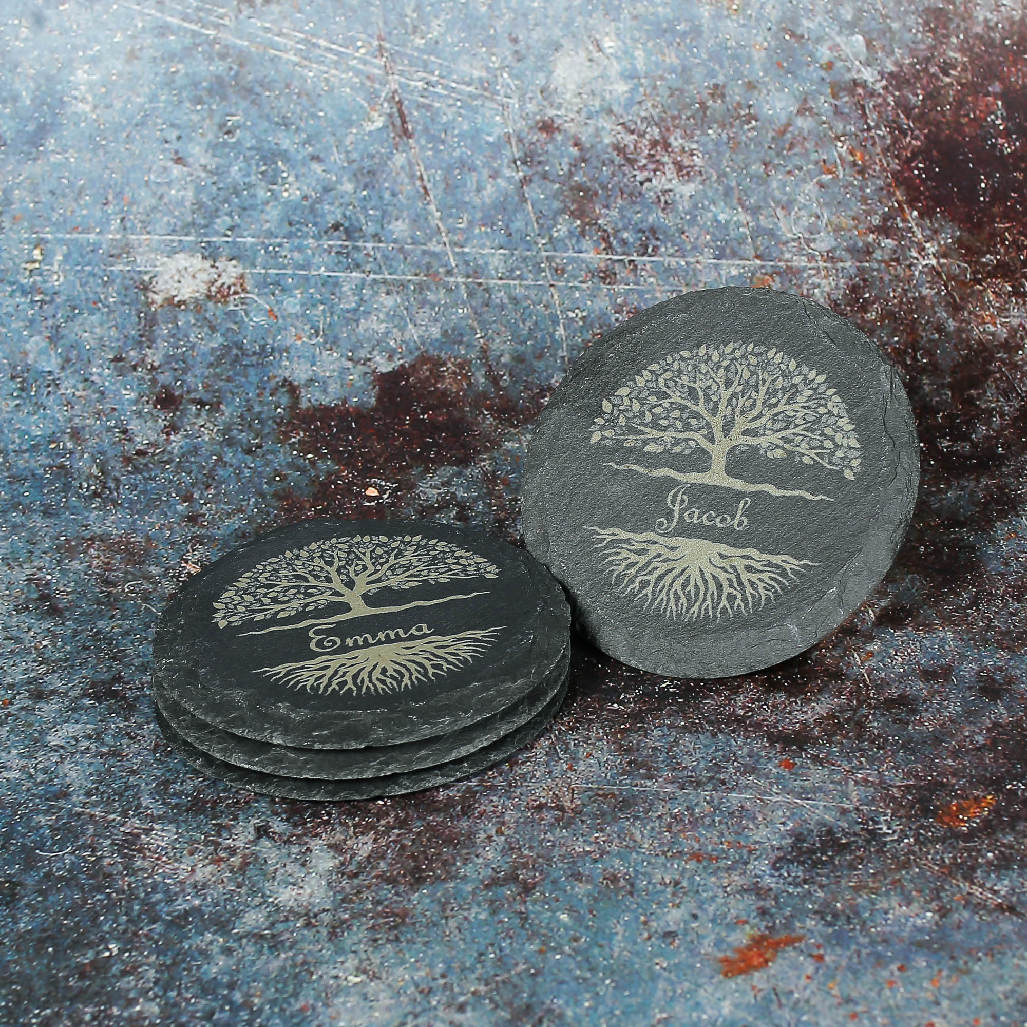 Personalised round slate coasters with a tree of life and name engraved between the tree and soil.