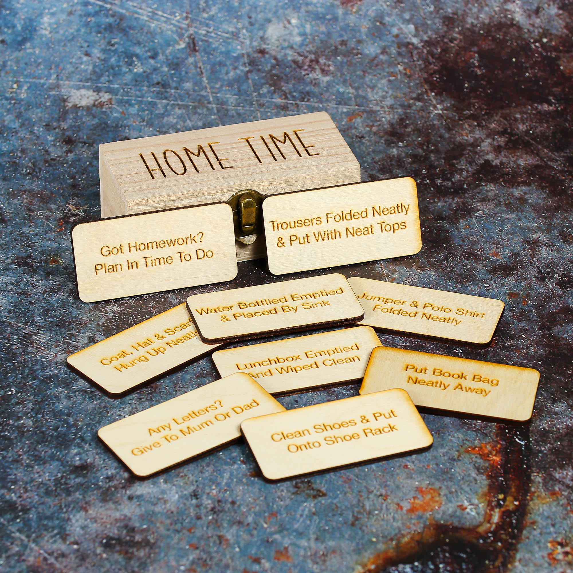 Wooden storage box with Home Time engraved on the lid and wooden tokens with engravings such as put book bag away,water bottled emptied and placed by sink and other home time task examples on them.