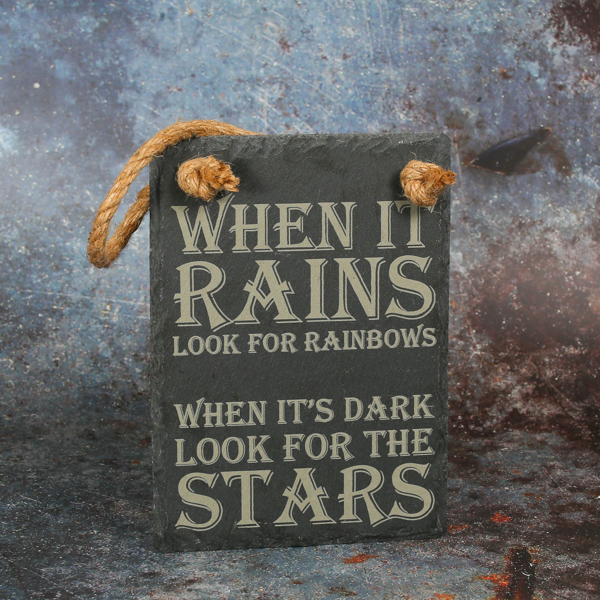 Rectangular slate sign laser engraved with "when it rains look for rainbows. When it's dark look for the rainbows.". There are two holes at the top which are looped with jute rope.
